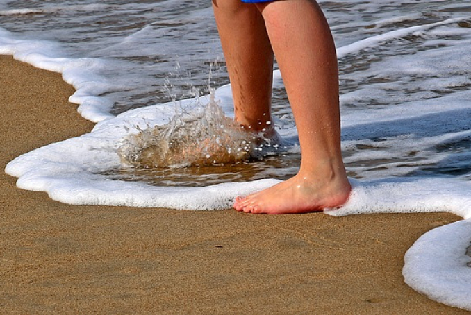 pieds d'un enfant au bord de l'eau sur une plage