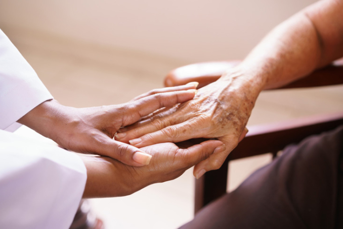 Infimière tenant les mains d'une personne âgée