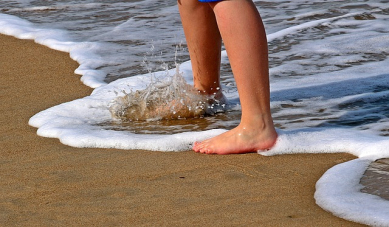 pieds d'un enfant au bord de l'eau sur une plage