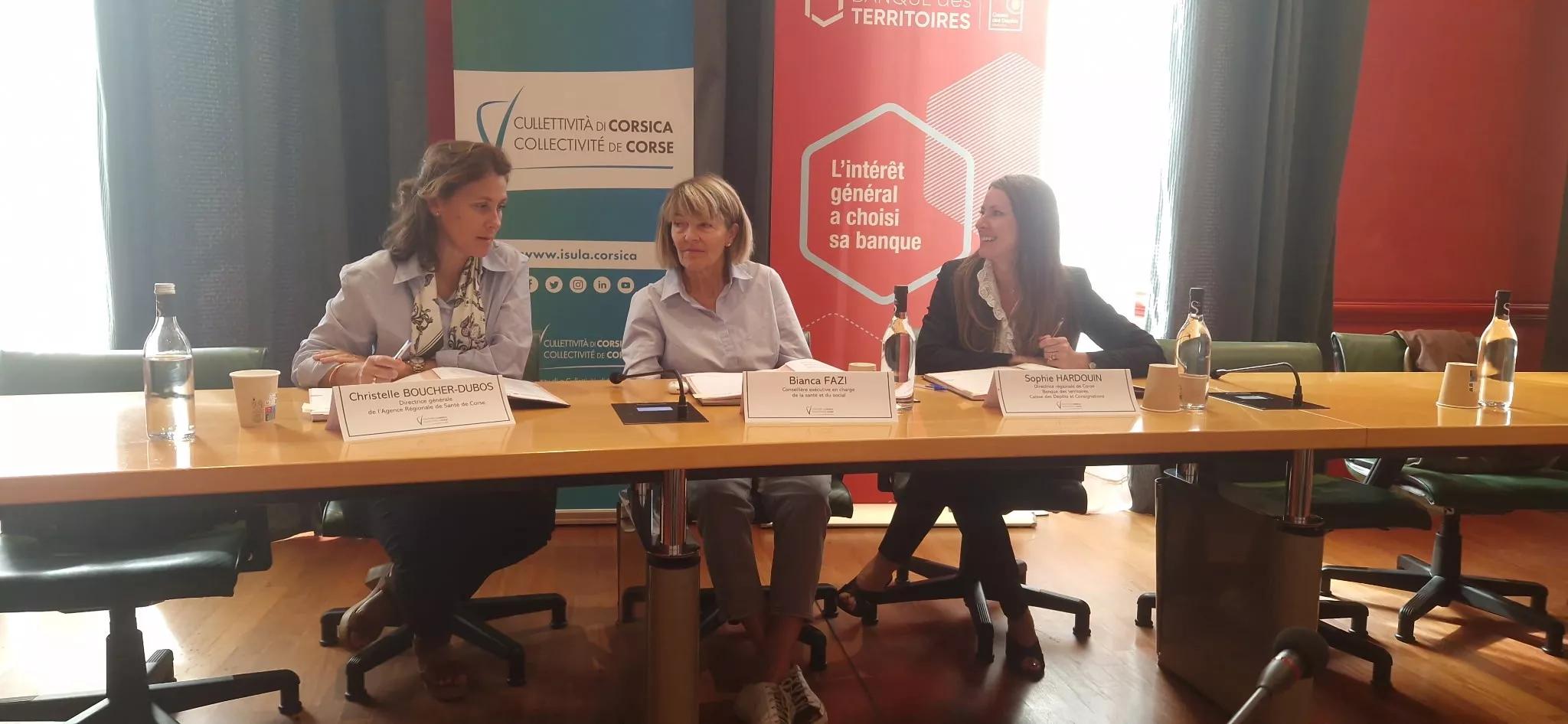 3 femmes assises en tribune pour signer une convention 
